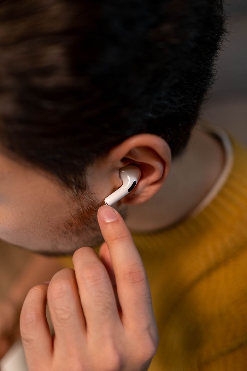 Person wearing a white wireless earbud in their ear