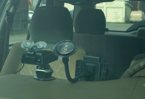 Compact dash camera device mounted behind the rearview mirror on a windshield