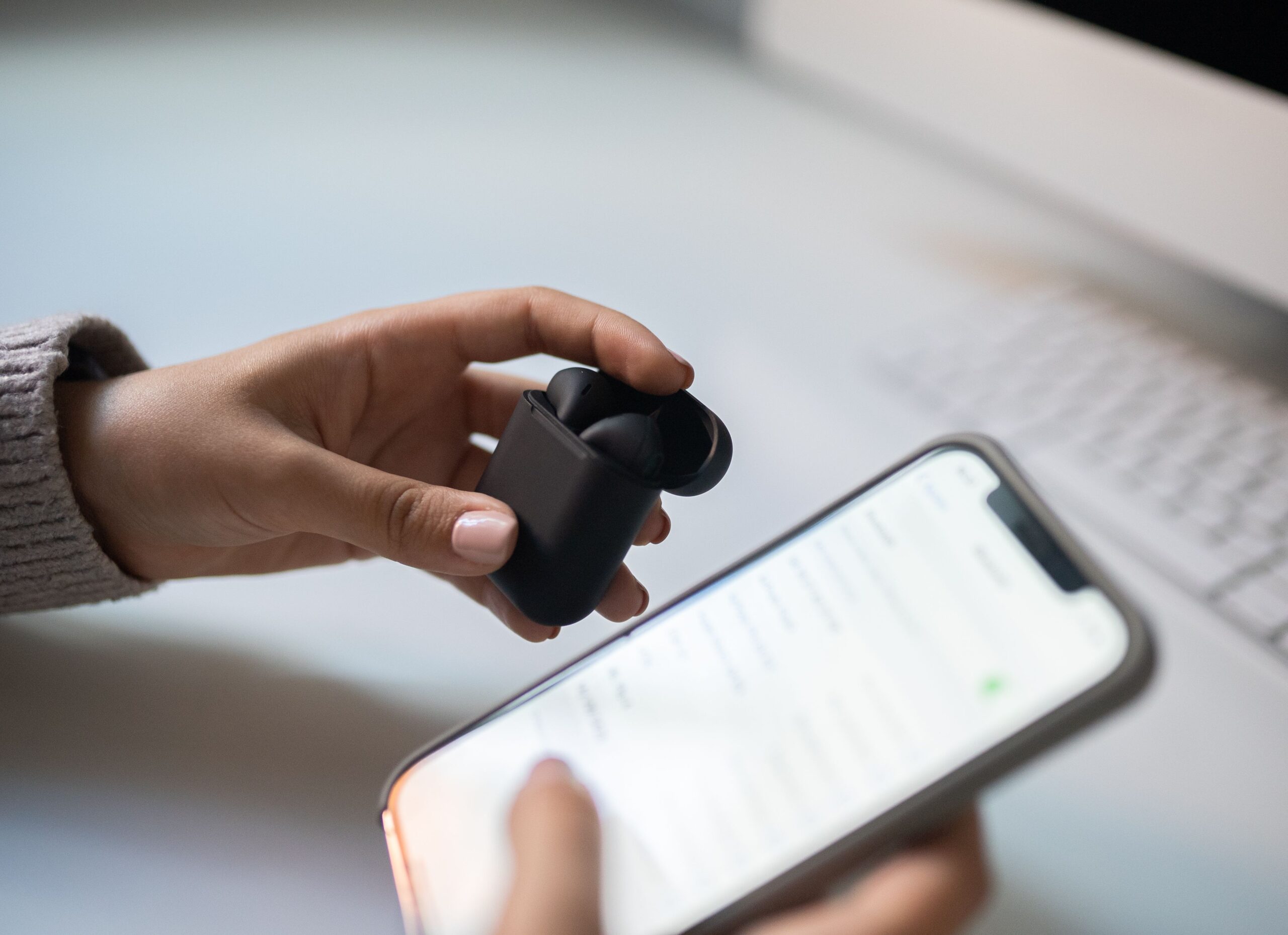 Hand holding open wireless earbuds case next to a smartphone during Bluetooth pairing Hand holding open wireless earbuds case next to a smartphone during Bluetooth pairing