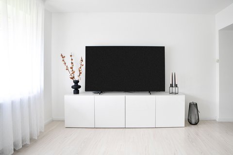 Wall-mounted flat screen TV similar to the Panasonic TH-65GX600K in a living room Wall-mounted flat screen TV similar to the Panasonic TH-65GX600K in a living room
