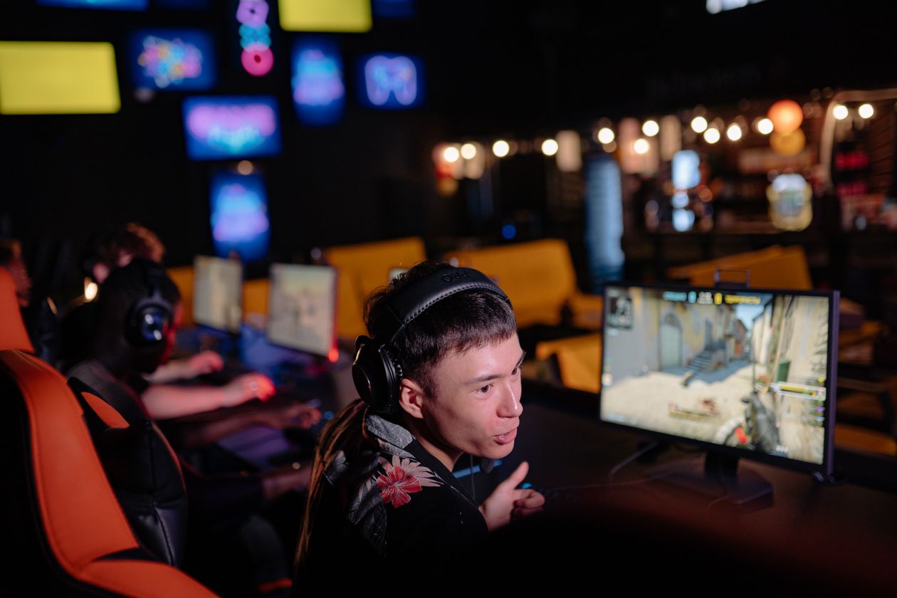 Person wearing a wireless headset while gaming at a computer Person wearing a wireless headset while gaming at a computer