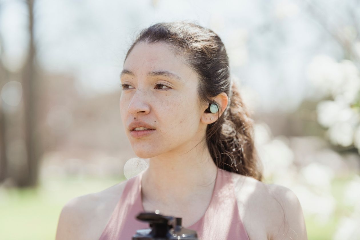Person wearing a wireless earbud while listening to music Person wearing a wireless earbud while listening to music