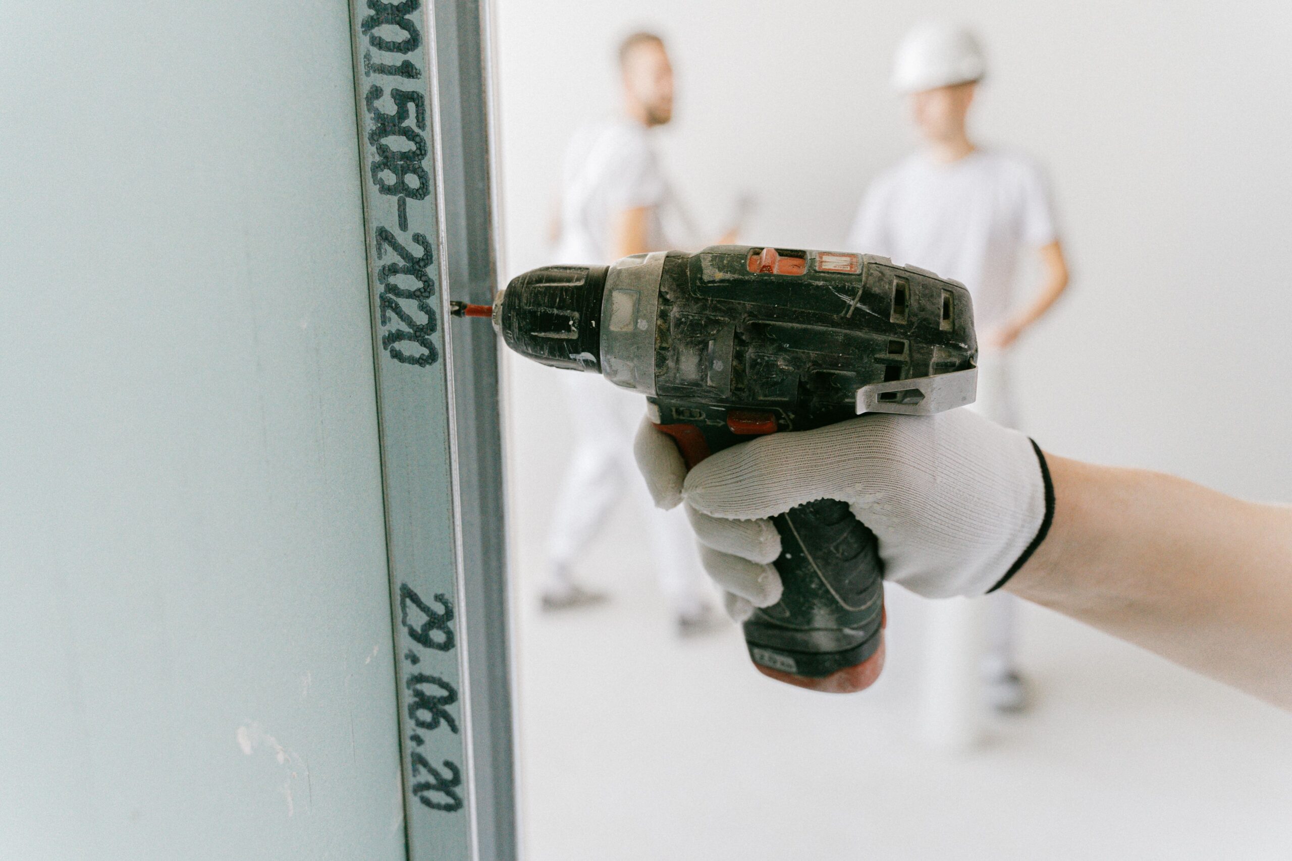 Hand using a power drill to install a mounting bracket Hand using a power drill to install a mounting bracket