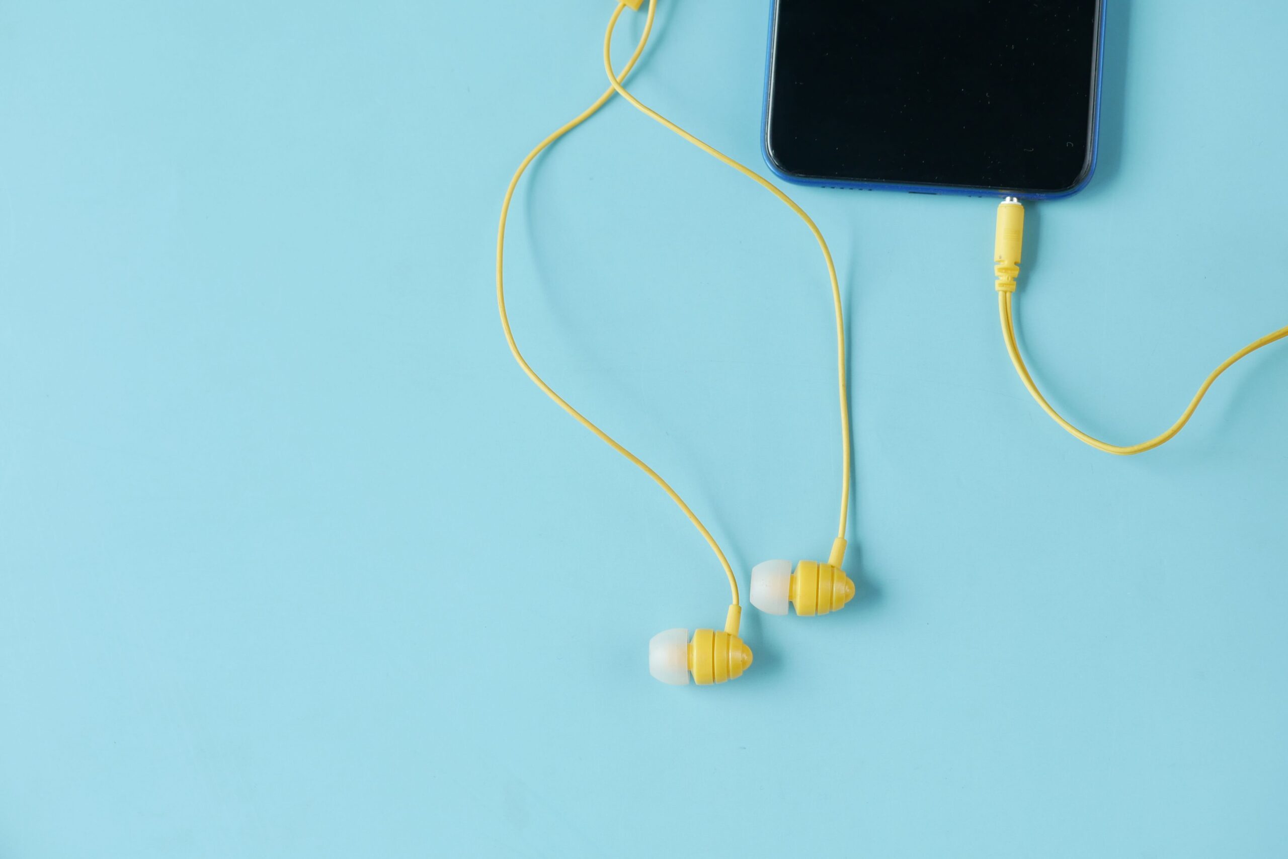 Wired earphones hanging with soft shadow against a wall Wired earphones hanging with soft shadow against a wall