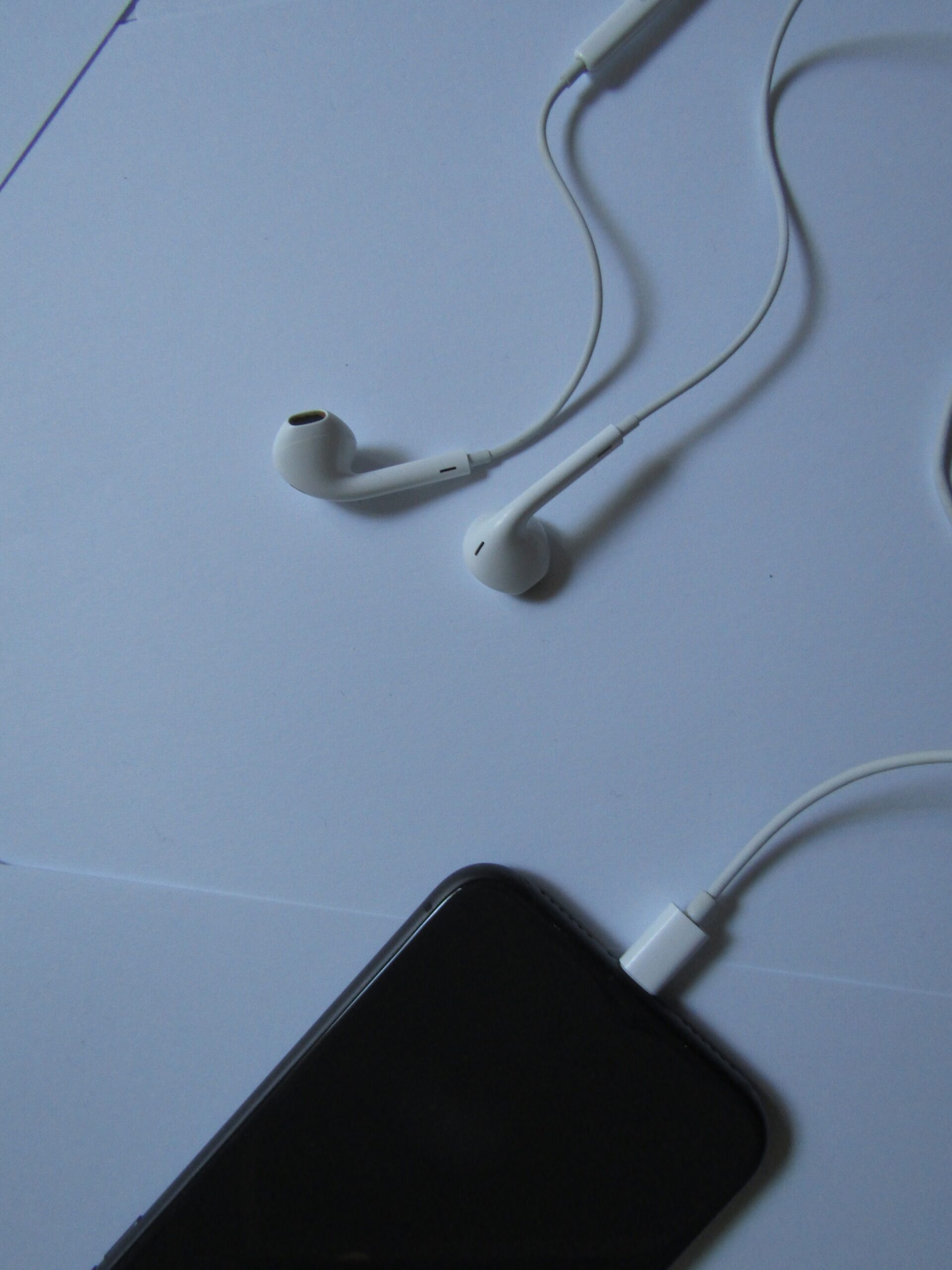 Wired earphones connected to a smartphone on a light surface Wired earphones connected to a smartphone on a light surface