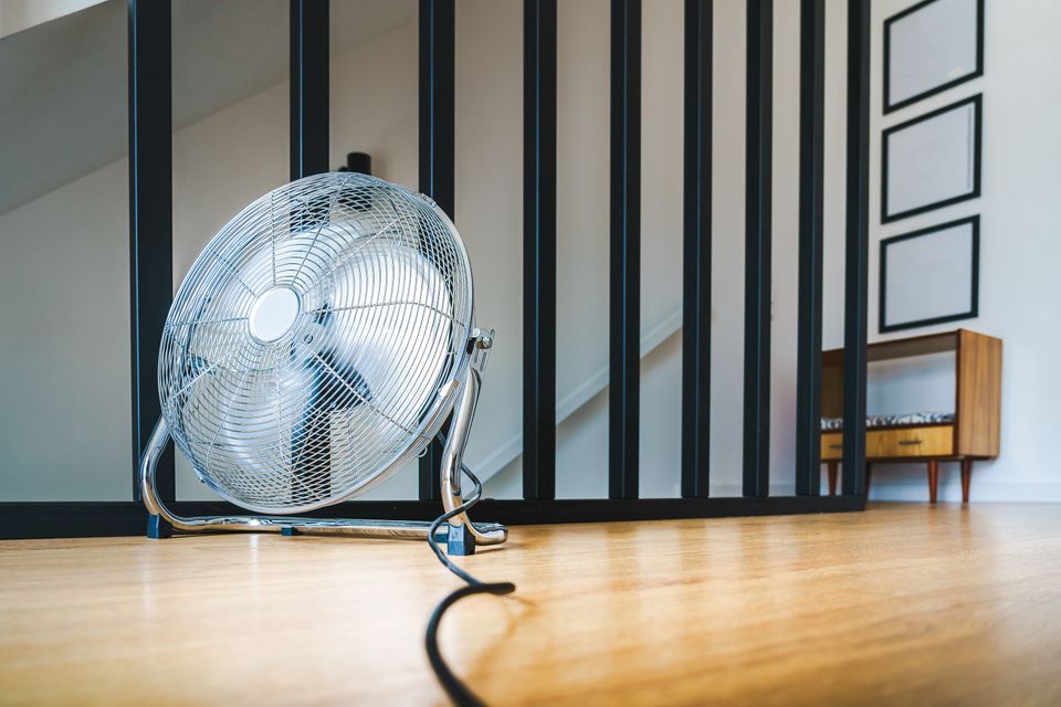 Portable electric fan on wooden floor for home cooling Portable electric fan on wooden floor for home cooling