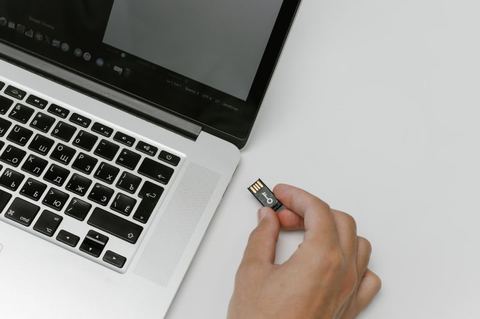 Compact USB WiFi dongle held near a laptop port Compact USB WiFi dongle held near a laptop port