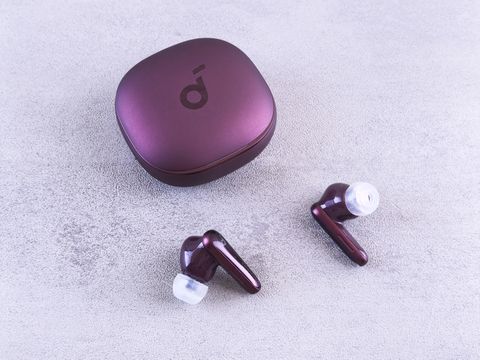 Anker Soundcore earbuds resting beside their charging case on a table Anker Soundcore earbuds resting beside their charging case on a table
