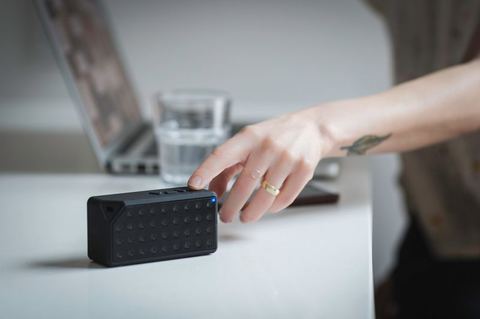 Compact Bluetooth speaker on a desk next to a phone during pairing Compact Bluetooth speaker on a desk next to a phone during pairing