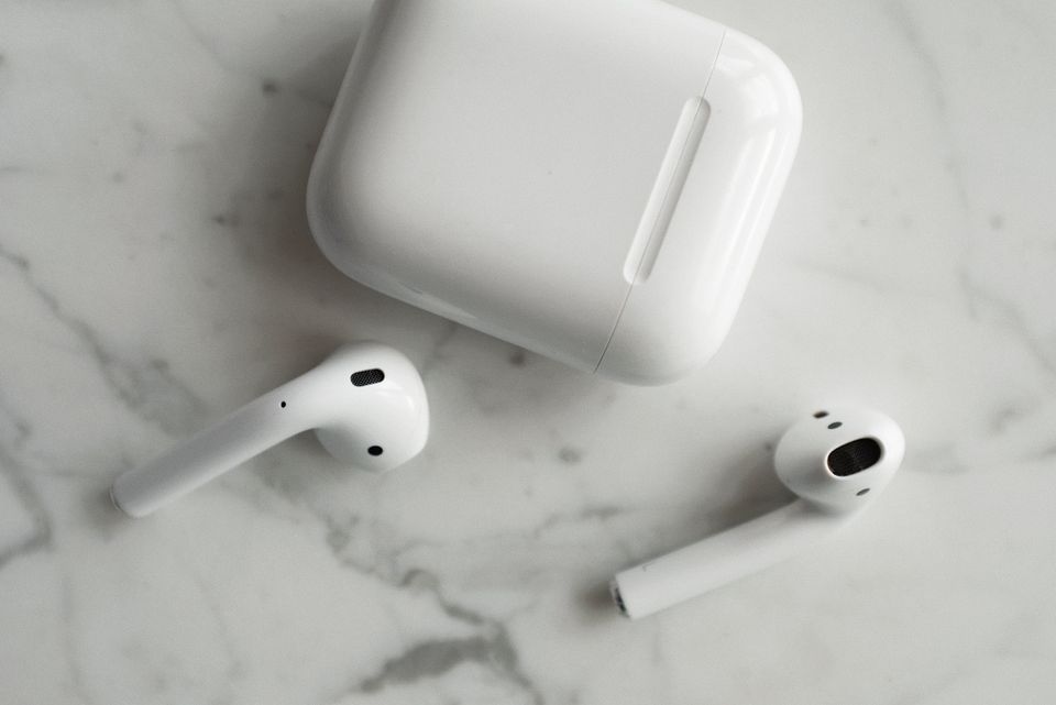 Transparent wireless earbuds and charging case on marble surface Transparent wireless earbuds and charging case on marble surface