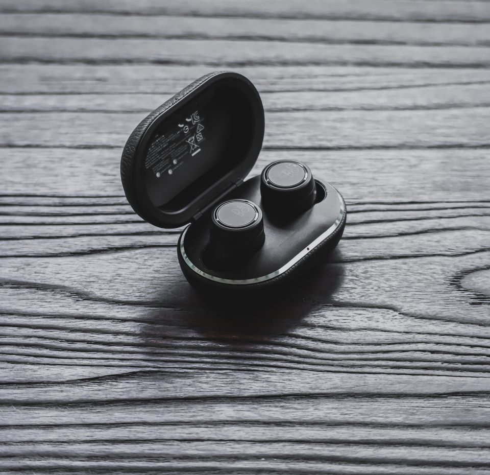 True wireless earbuds inside open charging case on wood surface True wireless earbuds inside open charging case on wood surface