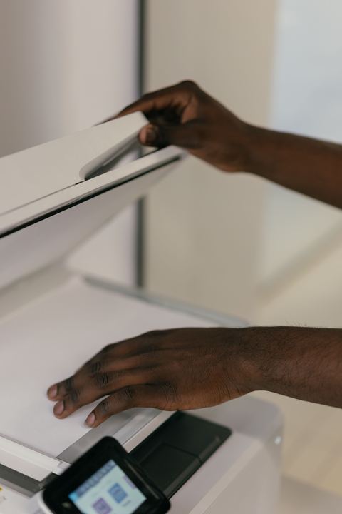 Hand placing a document onto a flatbed scanner glass bed