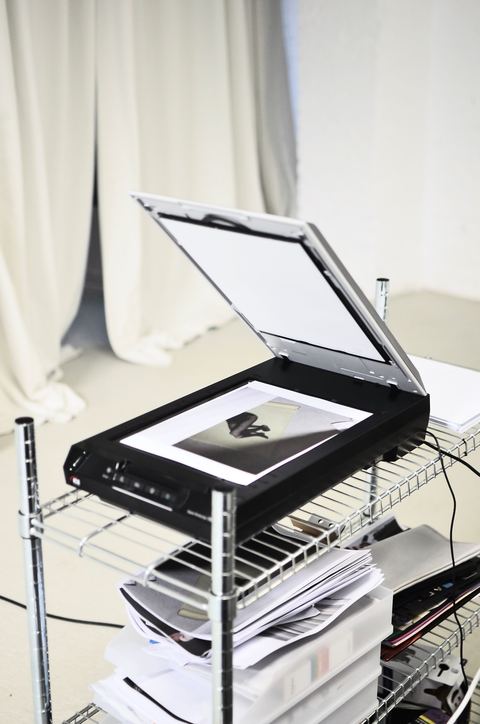 Slim flatbed scanner similar to Canon LiDE 25 opened on a shelf