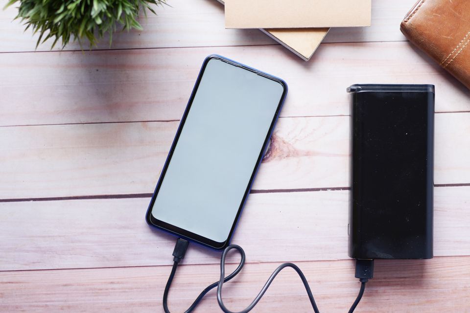 Smartphone charging from a power bank on a wooden desk