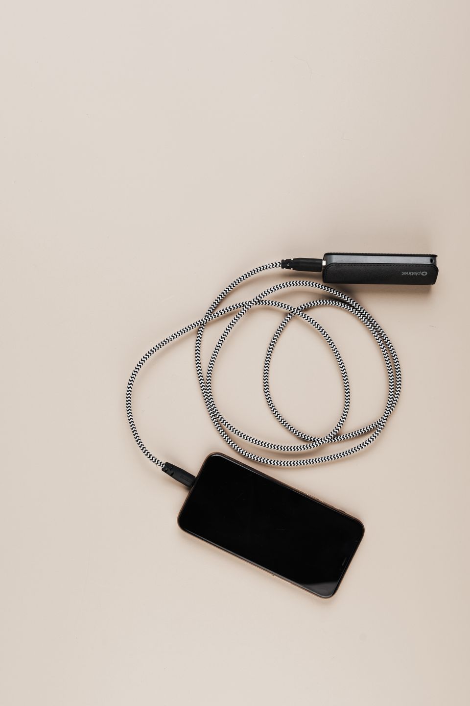 Mobile phone connected to a power bank with a coiled cable