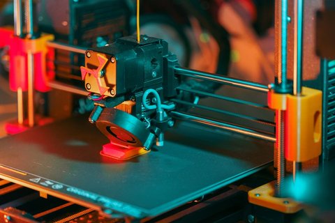 Macro shot of an Ender style extruder head actively printing with colored filament Macro shot of an Ender style extruder head actively printing with colored filament