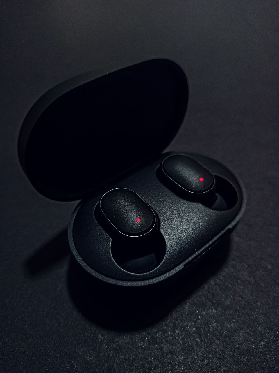 Sleek black wireless earbuds with charging case on dark background Sleek black wireless earbuds with charging case on dark background
