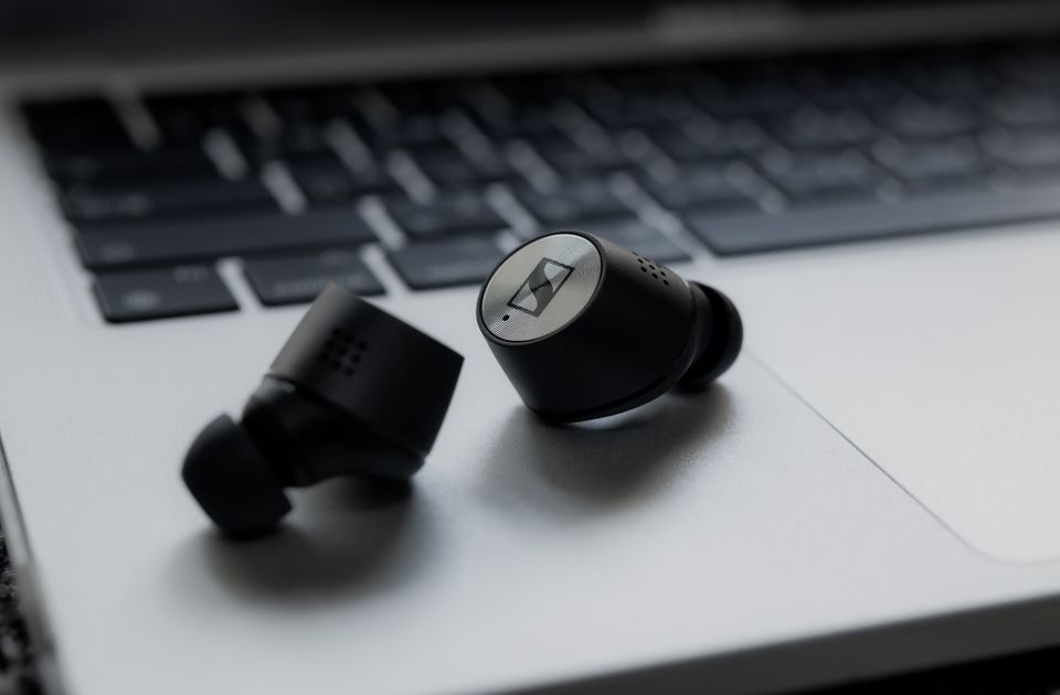 Black wireless earbuds resting on a laptop keyboard Black wireless earbuds resting on a laptop keyboard