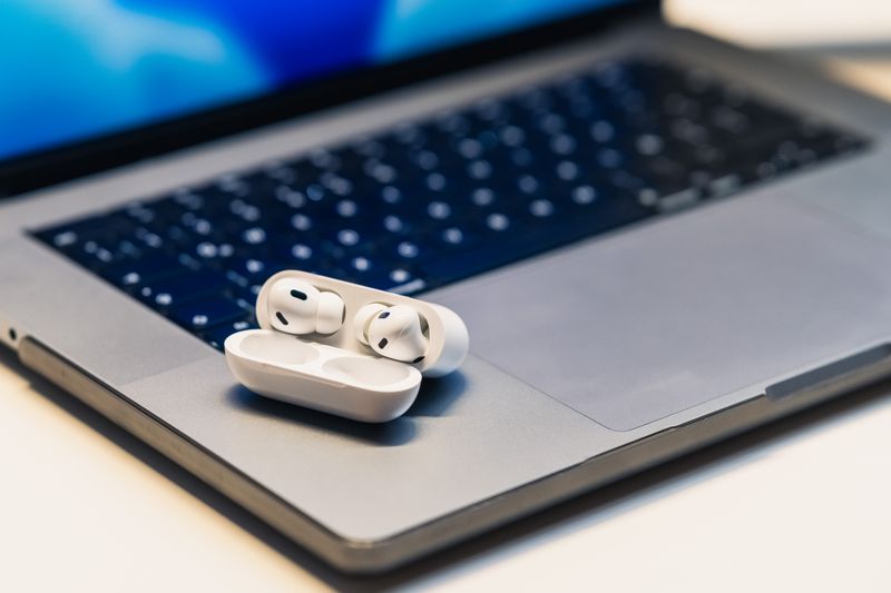 True wireless earbuds and charging case sitting on an open laptop True wireless earbuds and charging case sitting on an open laptop
