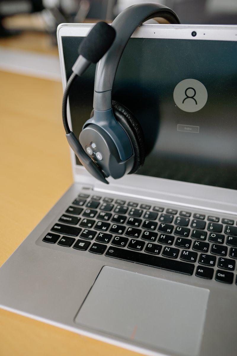 Over ear wired headset hanging on the edge of an open laptop Over ear wired headset hanging on the edge of an open laptop