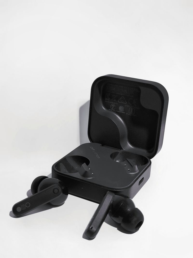 Black true wireless earbuds and open case on a plain background Black true wireless earbuds and open case on a plain background