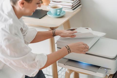 Person preparing paper documents for scanning near an office scanner