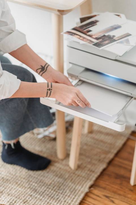 Person loading paper into the tray of an all-in-one printer Person loading paper into the tray of an all-in-one printer
