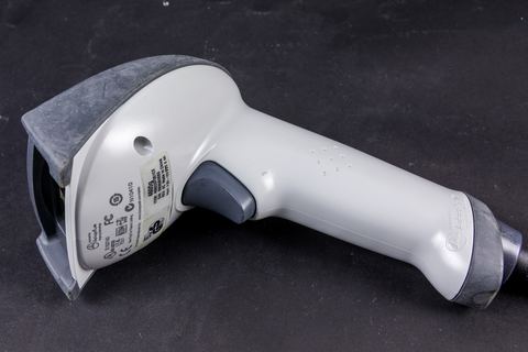 Angled view of a Honeywell handheld barcode scanner used at a retail counter Angled view of a Honeywell handheld barcode scanner used at a retail counter