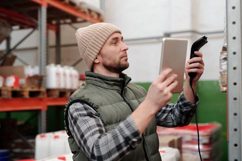Warehouse worker holding a handheld imaging scanner while checking inventory Warehouse worker holding a handheld imaging scanner while checking inventory
