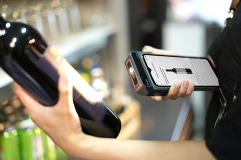 Store employee scanning a wine bottle barcode with a handheld scanner Store employee scanning a wine bottle barcode with a handheld scanner