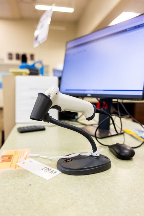 Handheld barcode scanner resting on its stand next to a desktop monitor Handheld barcode scanner resting on its stand next to a desktop monitor