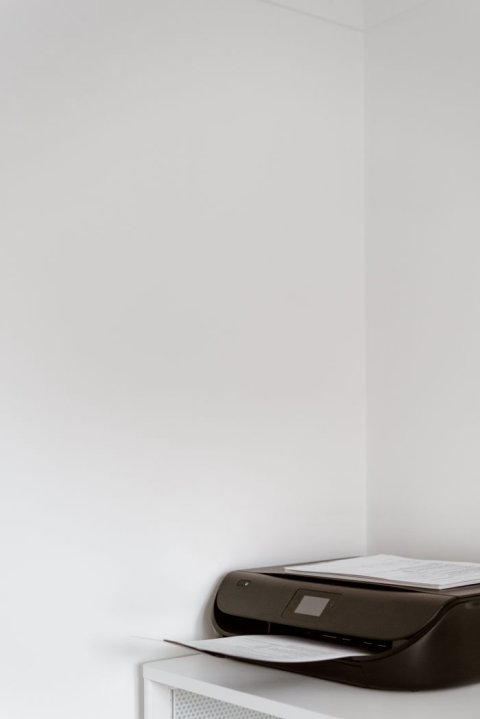 Compact monochrome laser printer sitting on a white office shelf Compact monochrome laser printer sitting on a white office shelf