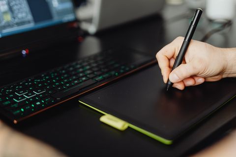 Artist hand holding Huion stylus pen while testing pressure sensitivity settings