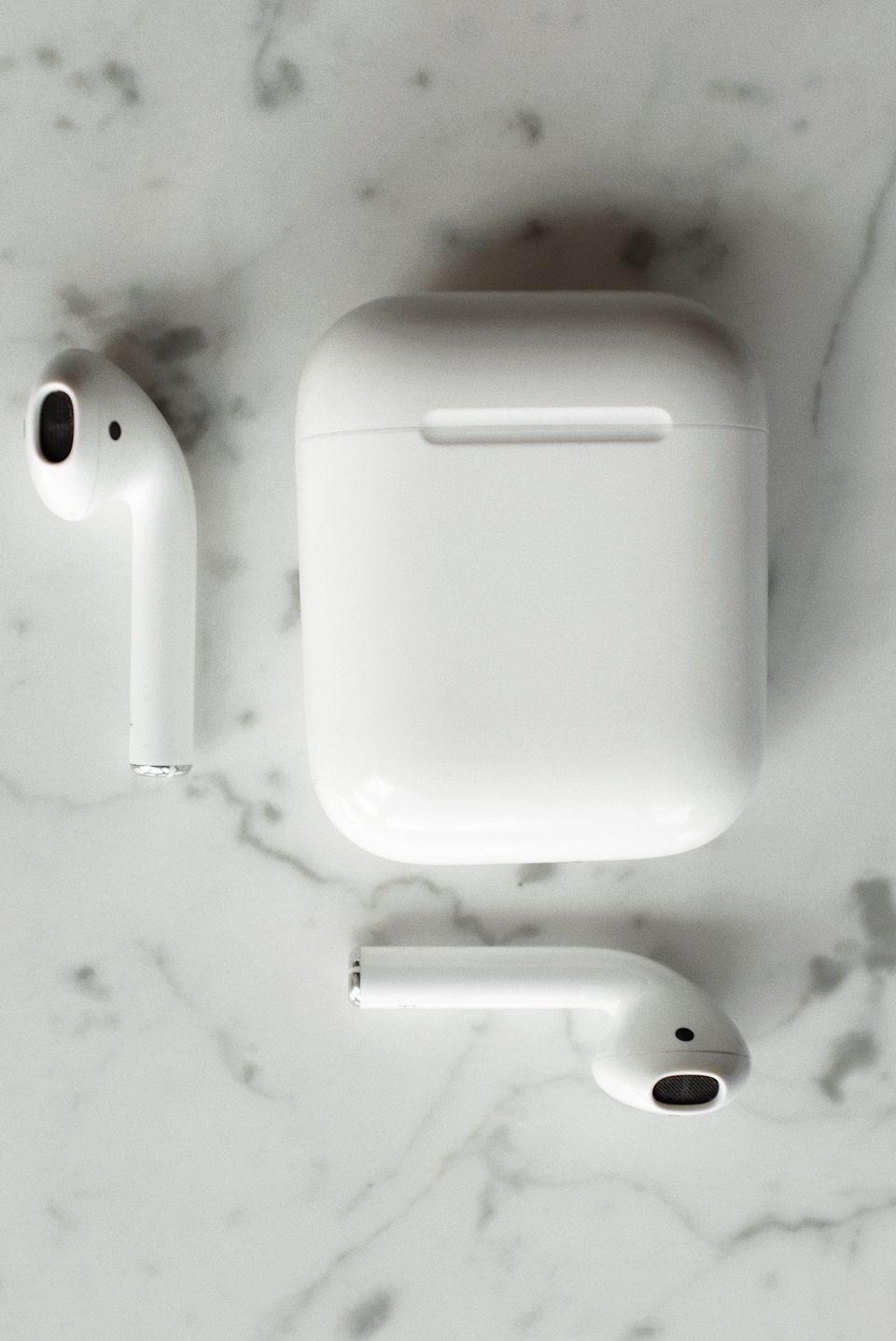 Wireless earbuds and charging case on marble background Wireless earbuds and charging case on marble background