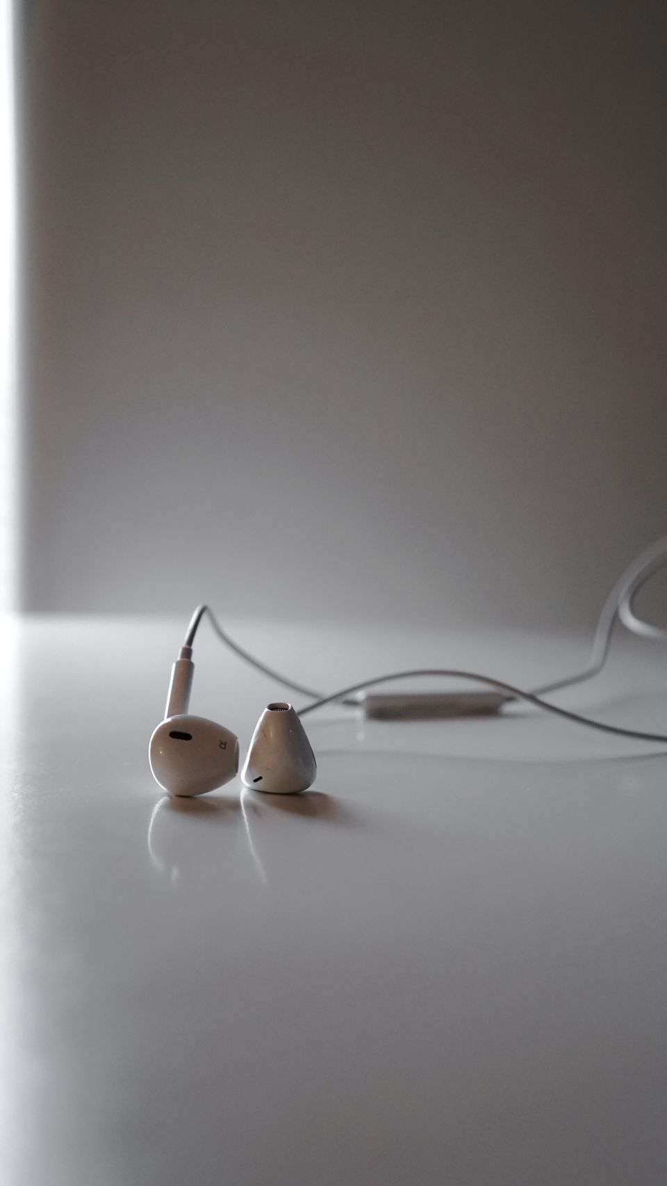 White earphones on a sleek surface in soft lighting White earphones on a sleek surface in soft lighting