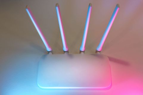 Close view of a wireless router with antennas lit under colored ambient lighting Close view of a wireless router with antennas lit under colored ambient lighting