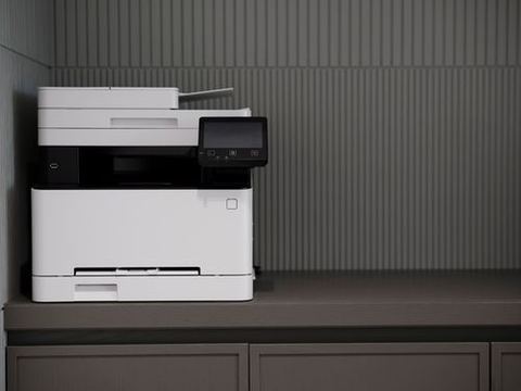 Compact black and white laser all-in-one printer on an office counter Compact black and white laser all-in-one printer on an office counter