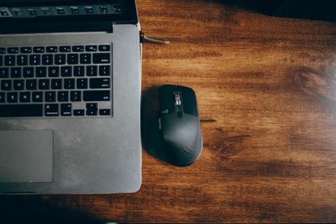 wireless mouse sitting on a wooden desk next to a laptop wireless mouse sitting on a wooden desk next to a laptop
