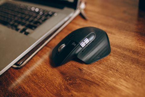 close view of an ergonomic wireless mouse on a wood grain desk close view of an ergonomic wireless mouse on a wood grain desk