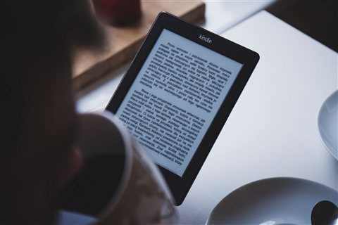 Close up of hand holding a modern e-reader against a plain background for setup Close up of hand holding a modern e-reader against a plain background for setup