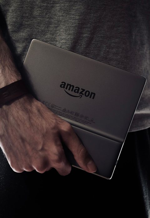 Amazon Kindle Paperwhite e-reader held in hand showing rear USB port area Amazon Kindle Paperwhite e-reader held in hand showing rear USB port area