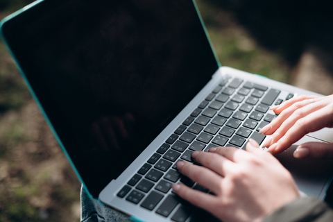 Person typing on a laptop keyboard while connected to WiFi Person typing on a laptop keyboard while connected to WiFi