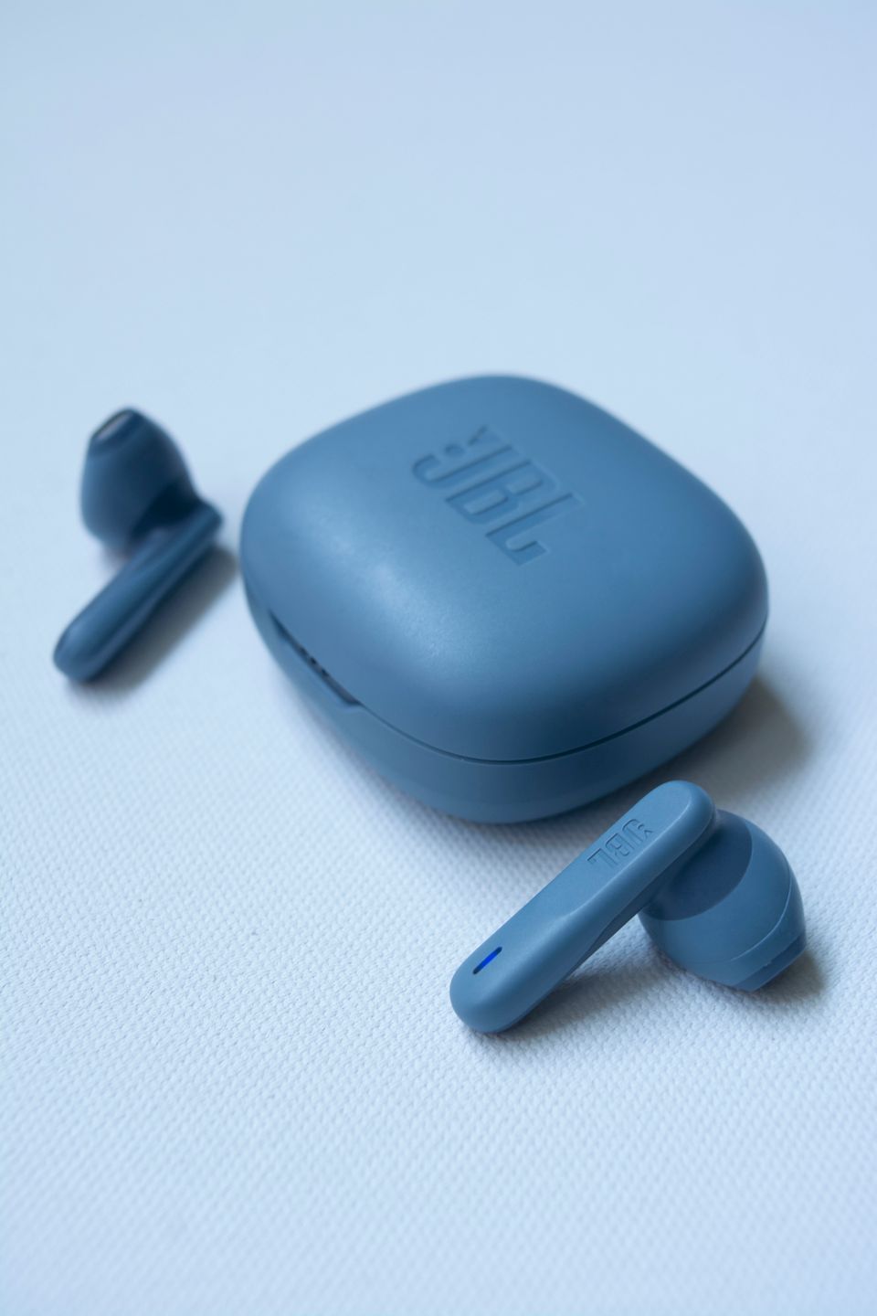 Small wireless earbuds and charging case on white background