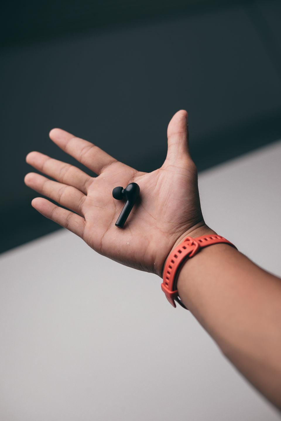 Close-up of a small wireless earbud held in a hand