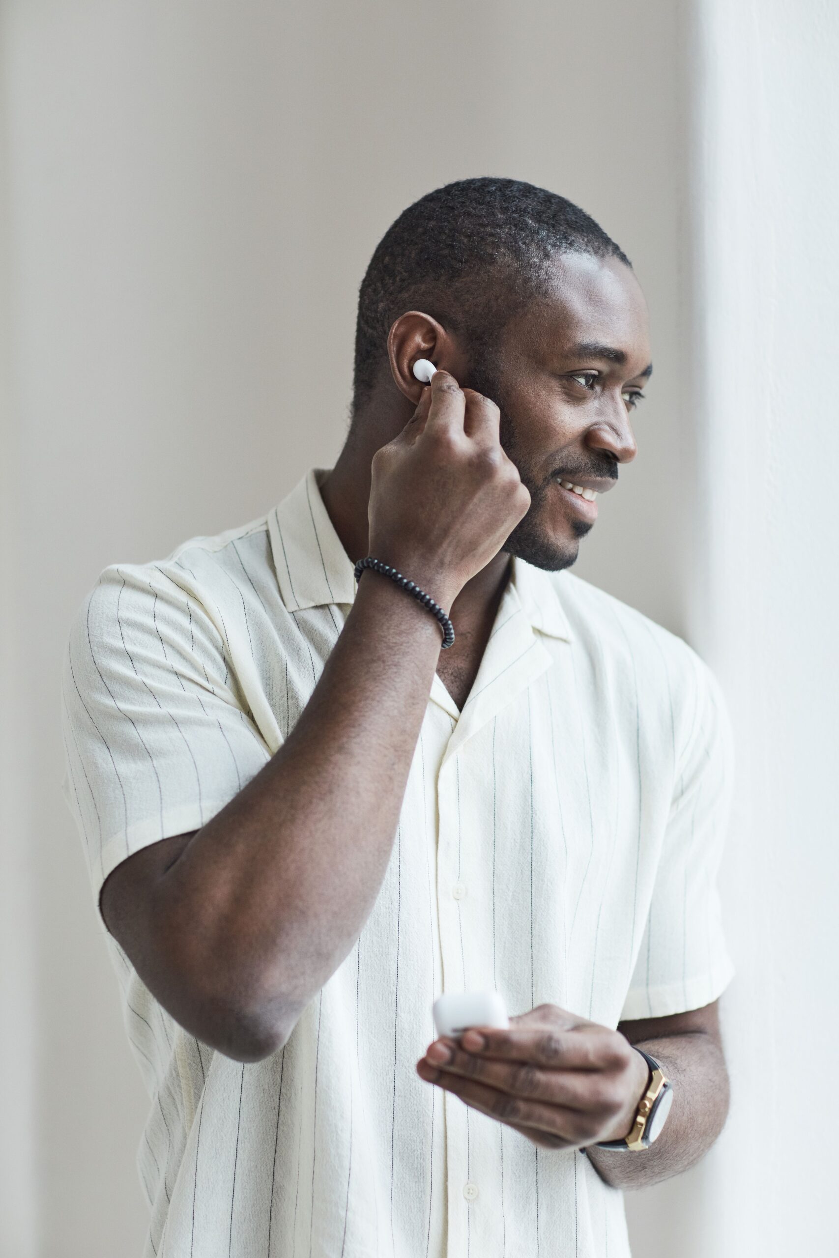 Person inserting a small wireless earbud comfortably into their ear Person inserting a small wireless earbud comfortably into their ear