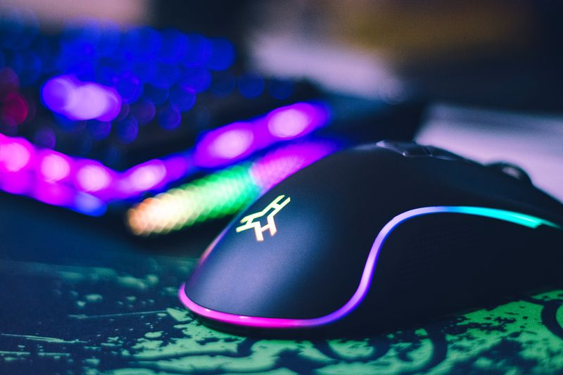 Onikuma CW906 style RGB gaming mouse glowing on a desk pad Onikuma CW906 style RGB gaming mouse glowing on a desk pad