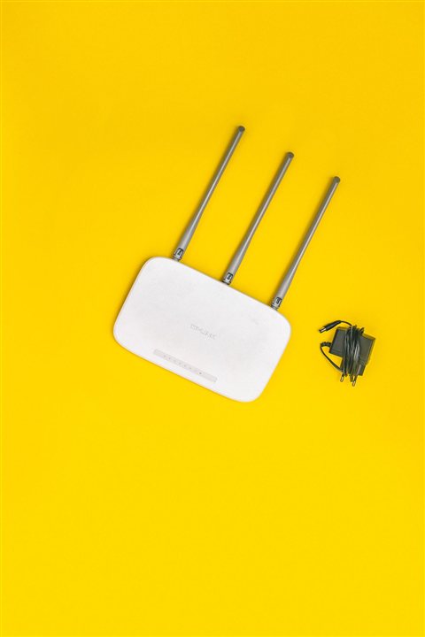White wireless router with three antennas on bright yellow background studio shot White wireless router with three antennas on bright yellow background studio shot