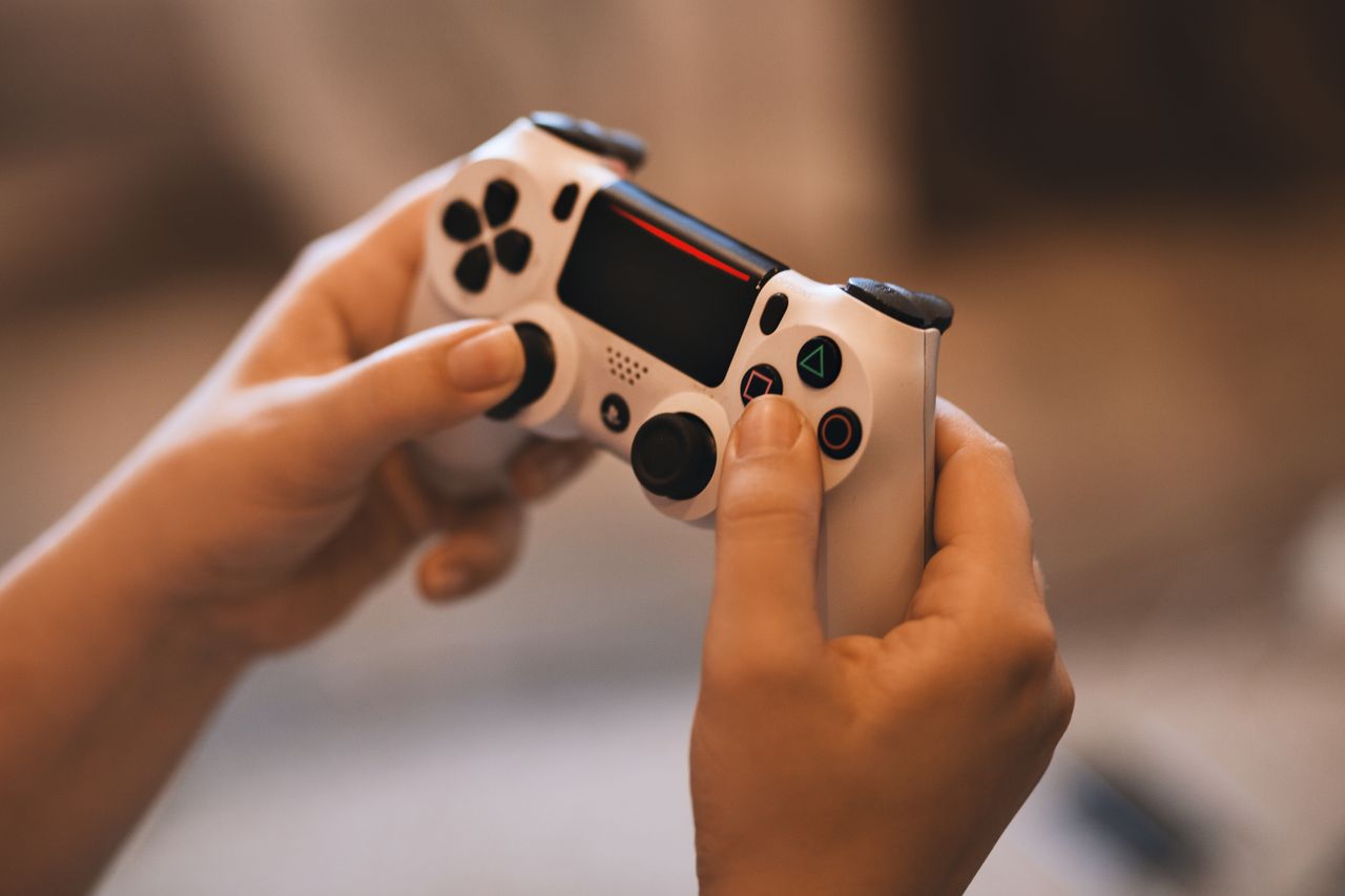 Person holding a wireless game controller indoors Person holding a wireless game controller indoors