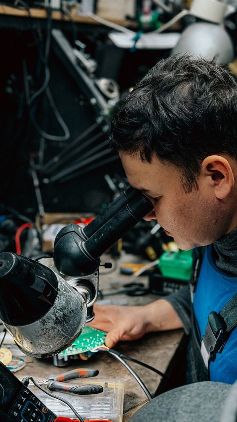 Technician using a magnifying scope to closely inspect a small circuit board Technician using a magnifying scope to closely inspect a small circuit board