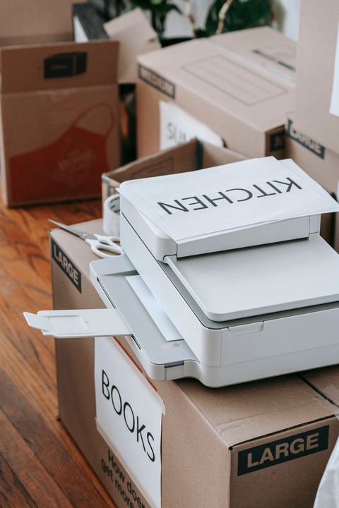 Printer sitting on top of moving boxes in a home office Printer sitting on top of moving boxes in a home office